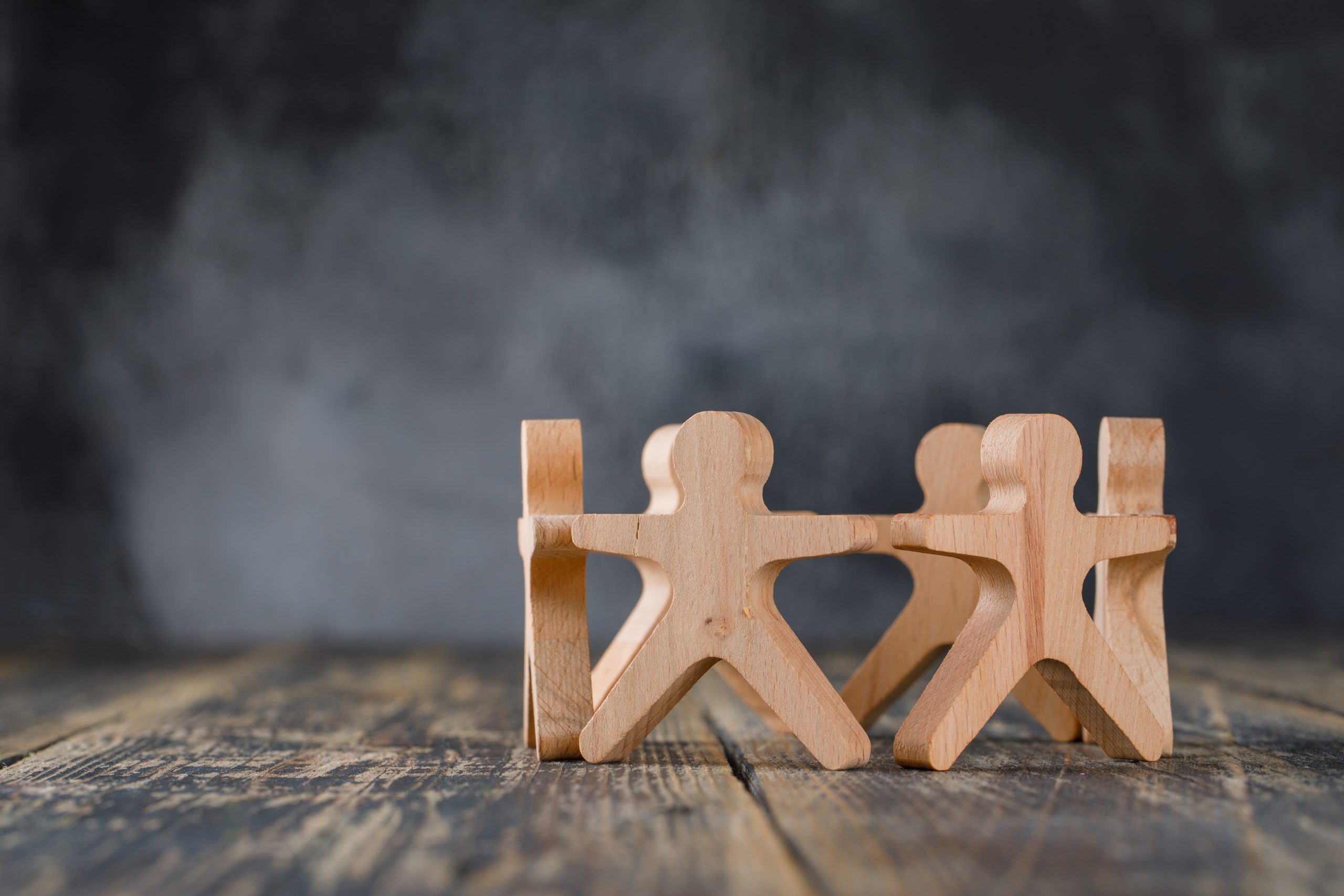 Business success and teamwork concept with wooden figures of people on wooden and foggy background side view. Business success and teamwork concept with wooden figures of people on wooden and foggy background side view.